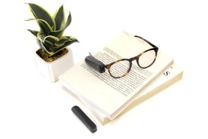 Brille mit Orcam MyEye 2.0 liegt auf einem Buch